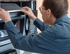 Appliance repair technician replacing a microwave vent filter in Naperville, IL