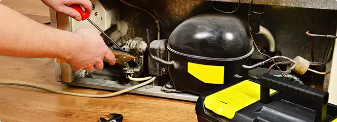 Refrigerator repair technician fixing the compressor and wiring in Naperville, IL