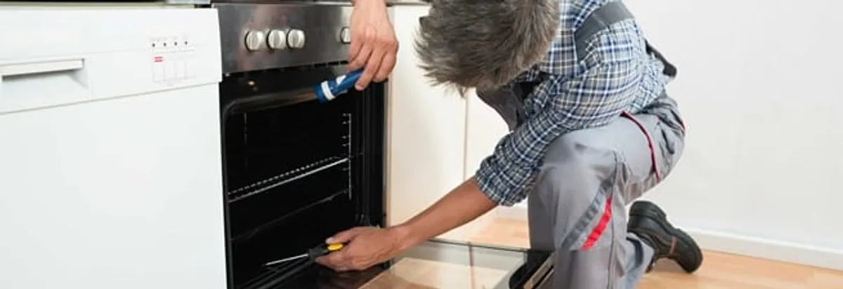 Oven repair technician inspecting and servicing an electric oven in Naperville, IL